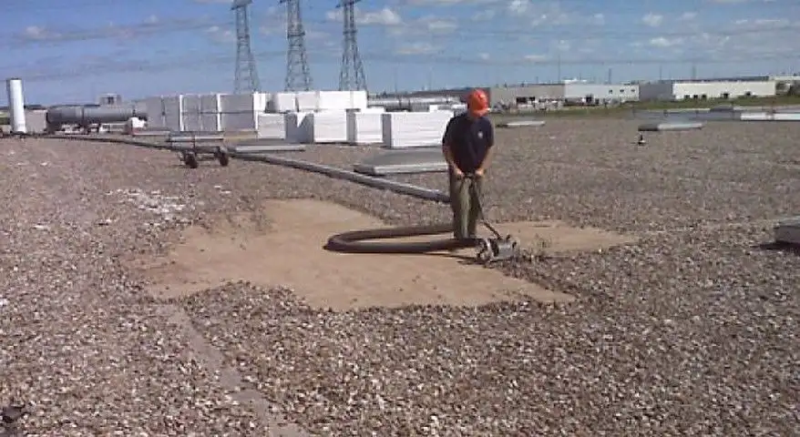 Vacaroof crew vacuuming gravel from a flat commercial roof in Barrie
